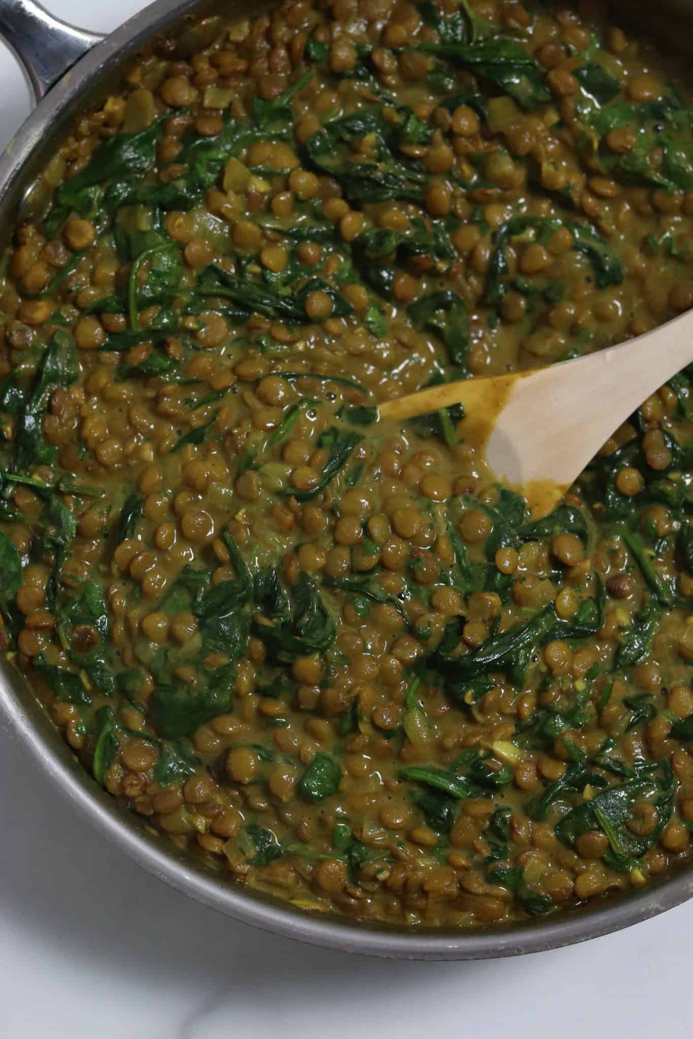 An overhead shot of a pan of coconut curry lentils with spinach