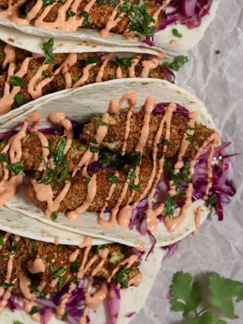 A close-up of a crispy air fryer avocado taco drizzled with spicy paprika aioli