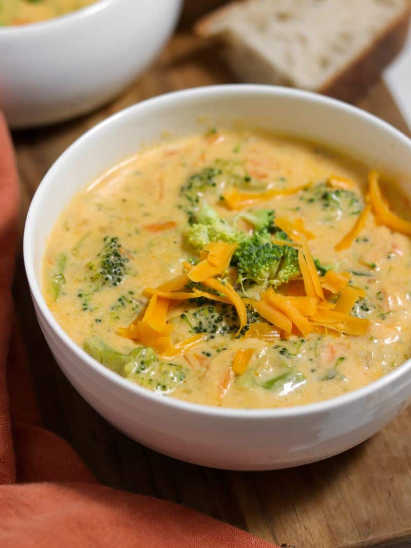 A bowl of creamy broccoli cheddar soup with shreds of cheddar cheese on top