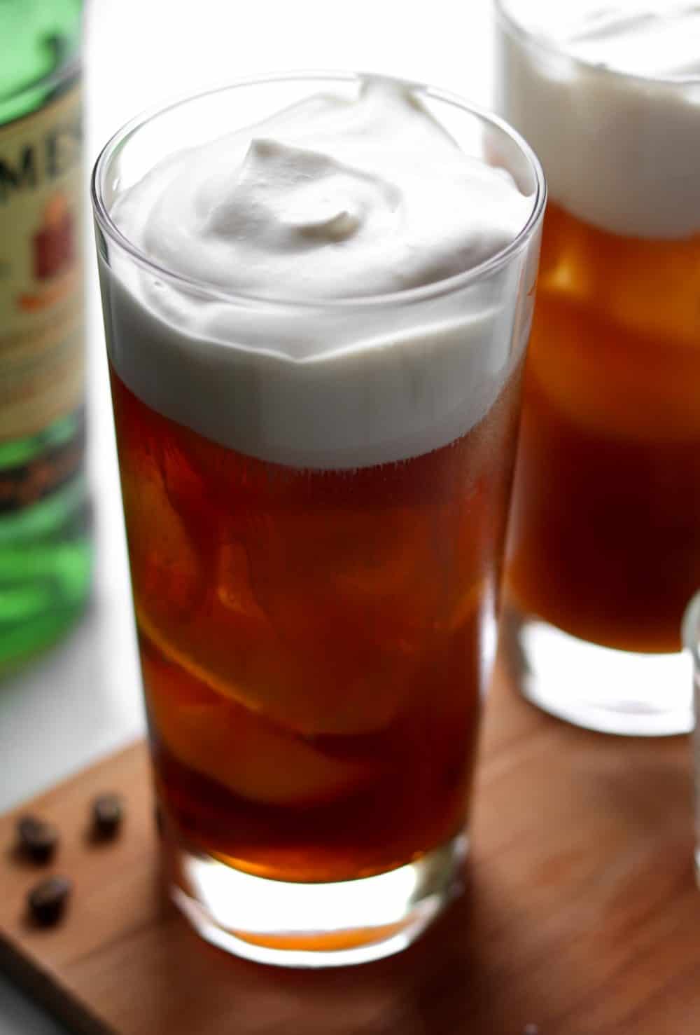 A tall glass full of Irish iced coffee, topped with sweet, fluffy whipped cream