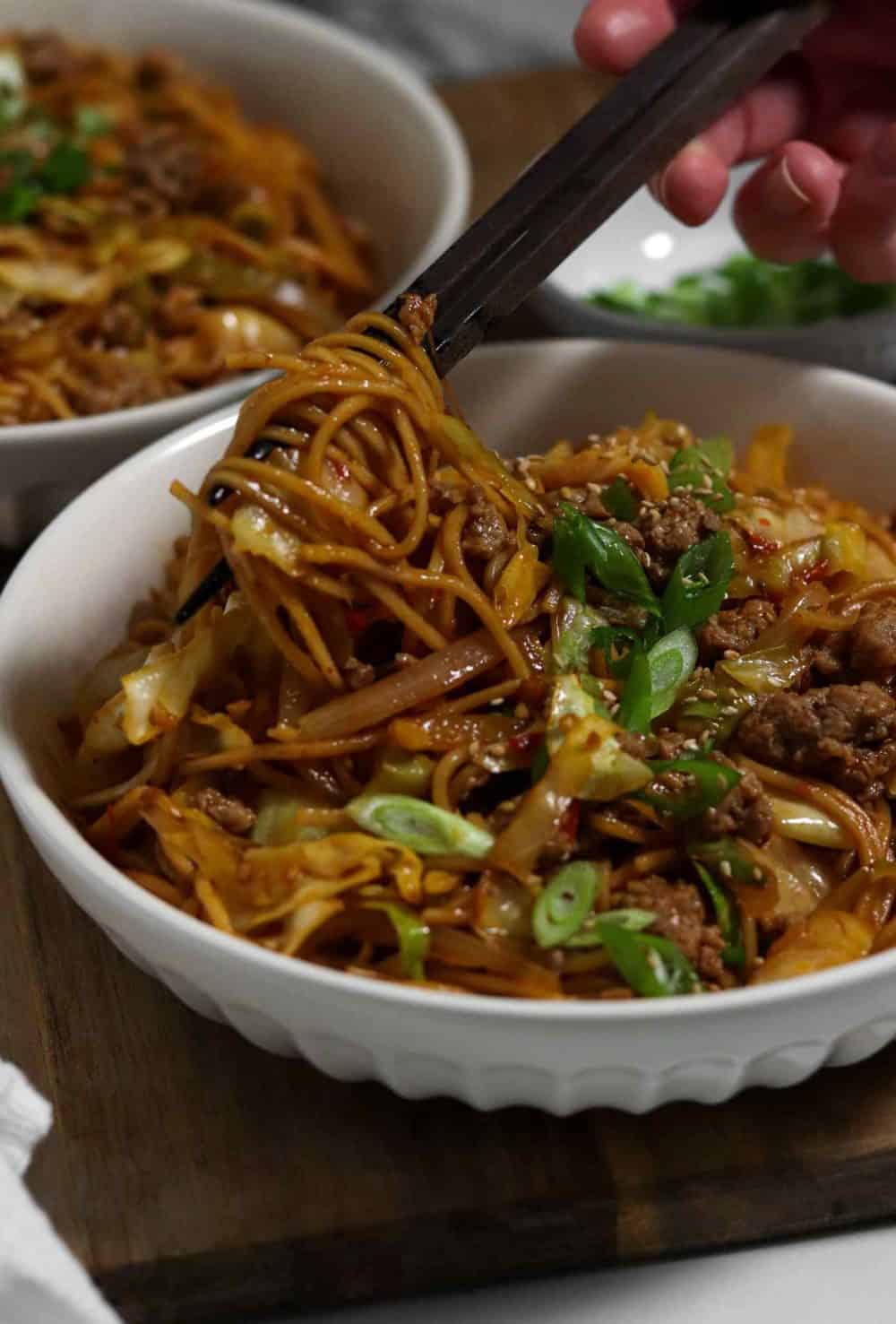 Picking up a tangle of spicy pork noodles with chopsticks