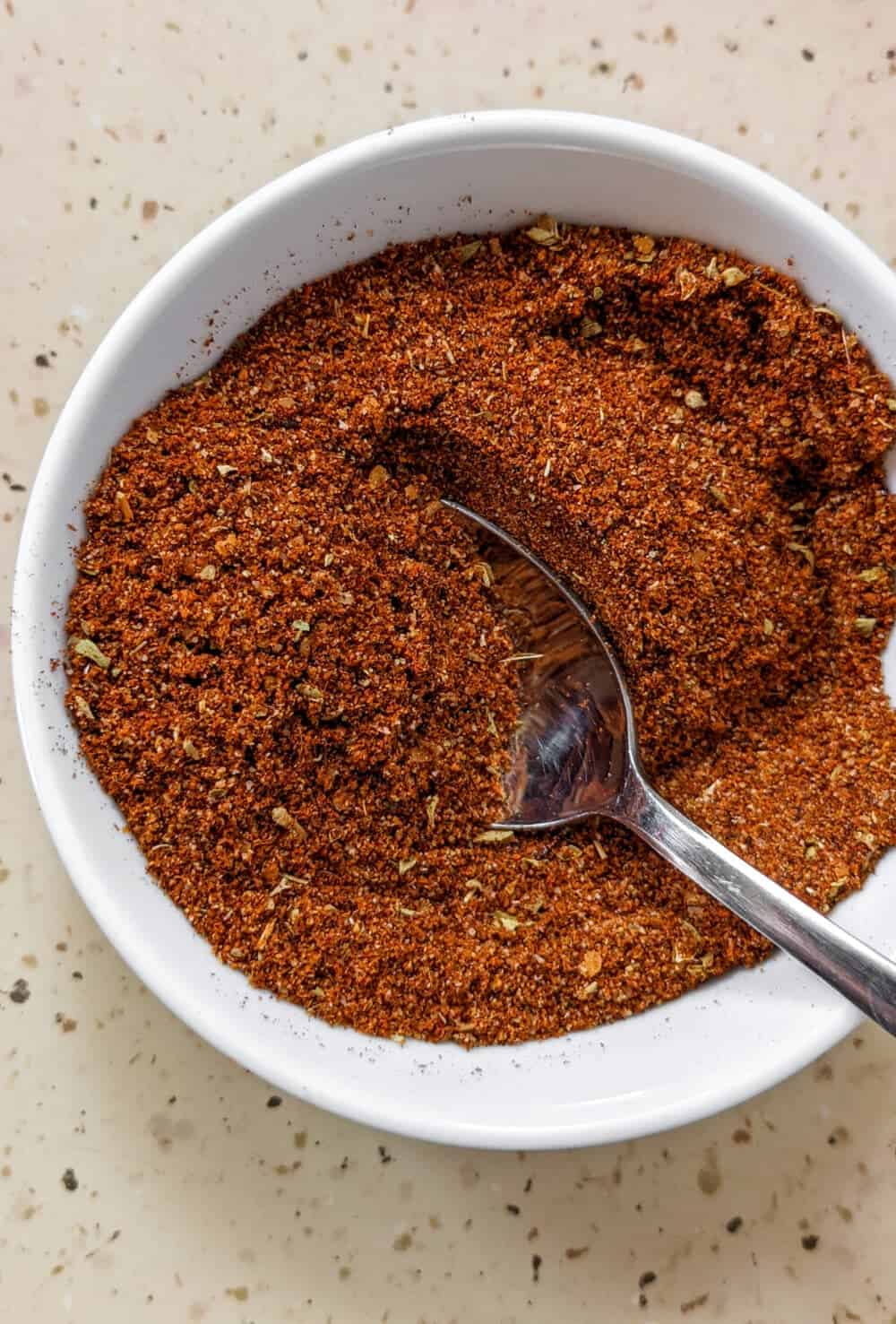 A small bowl of homemade taco seasoning with a spoon resting in it