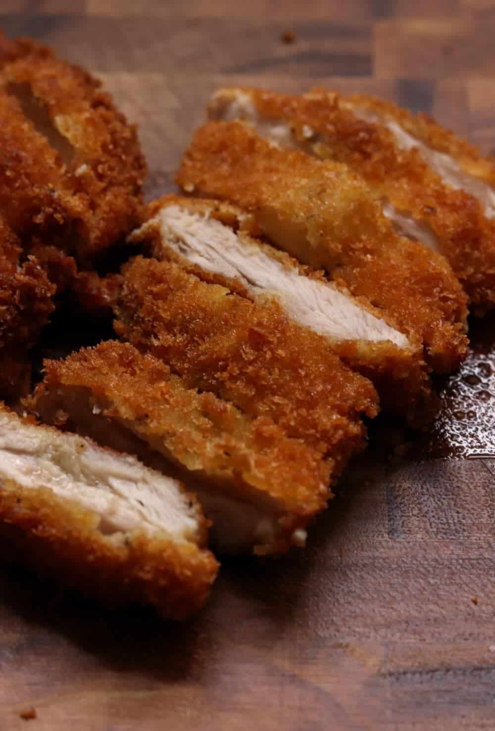 A close-up of perfectly crispy, golden-brown chicken katsu sliced up on a cutting board